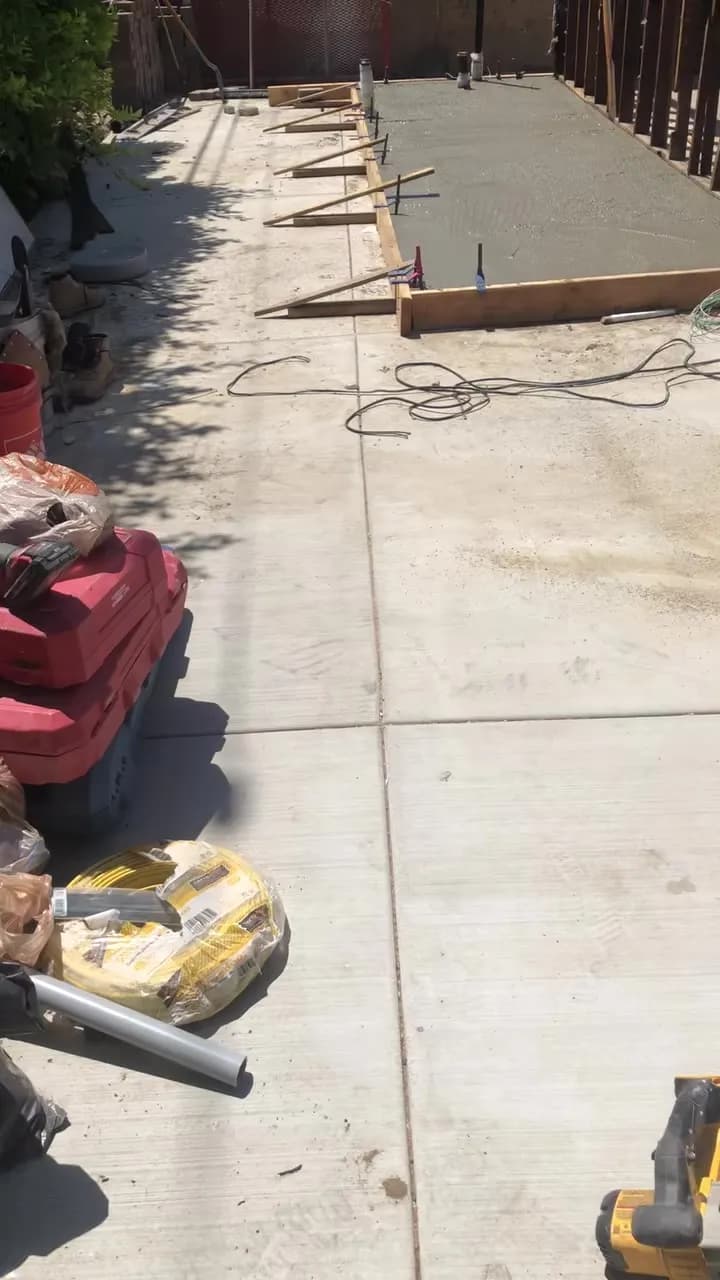 New concrete slab poured alongside a side yard with wood forms